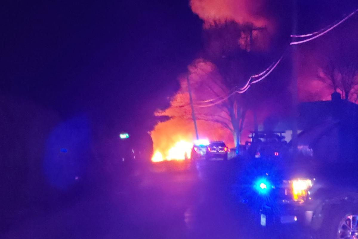 Blue lights from police car with barn on fire behind.