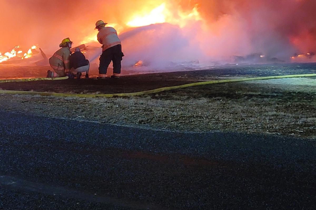 Two fire fighters fighting the fire of the fully engulfed fire from the ground.