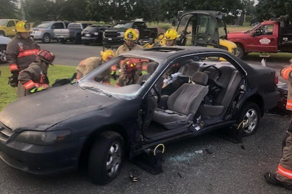 Severely damaged car being used by fire fighters for training purposes